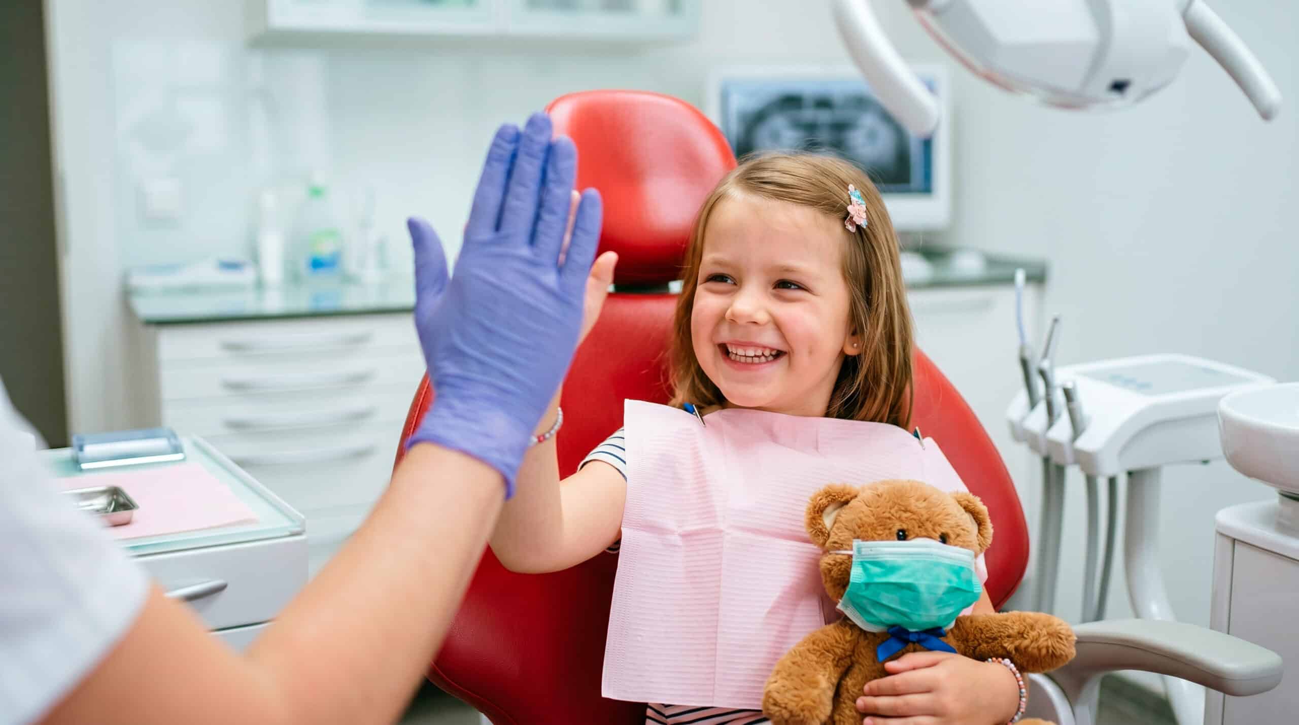 Happy child gives dentist a high five after a positive dental visit